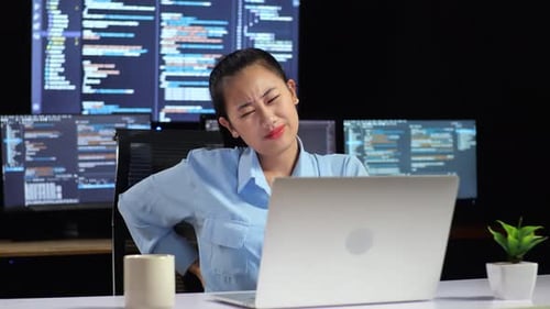 Asian Female Programmer Having A Backache While Writing Code By A Laptop Using Multiple Monitors