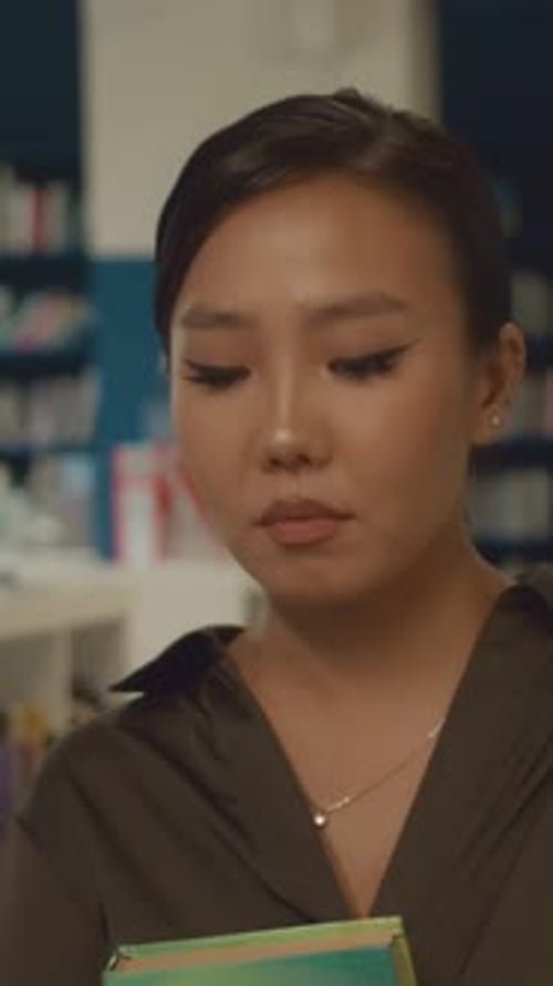 Asiatisches Mädchen verlässt die Bibliothek mit Büchern für Prüfungen