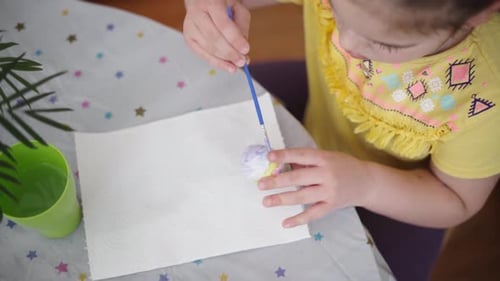 Kind im Vorschulalter malt Ostereier zu Hause in der Küche
