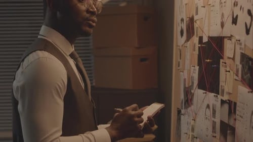 African American Detective Analyzing Evidence Board at Night Office