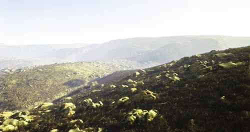 Rugged Landscape with Rocky Terrain and Distant Mountain Views at Sunrise