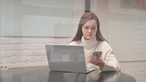 Woman Uses Phone and Laptop Indoors