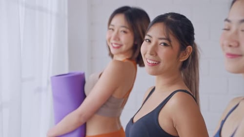 Smiling Women Holding Yoga Mats Indoors