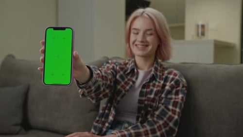 Woman Holding Green Screen Smartphone At Camera Smiling 20s Female Shows Cell Phone with Chroma Key