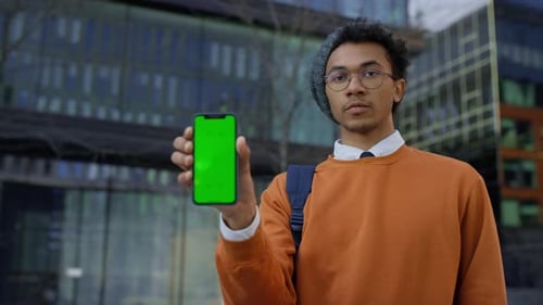 Man Holding Smartphone with Green Screen in City