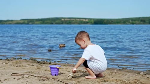 Small boy on river beach playing. Little child summer lifestyle.