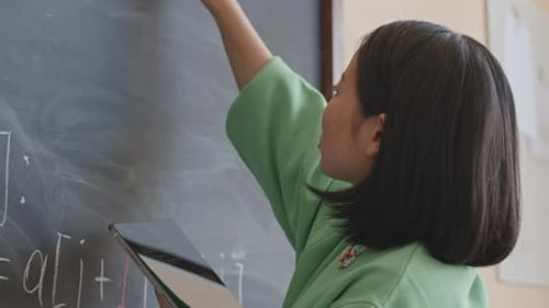 Woman Writes Math Equations on Blackboard Using Tablet