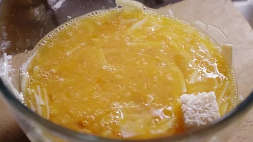 Adding Bread Cubes Into A Glass Bowl With Beaten Eggs. Toast Omelette Recipe. close up