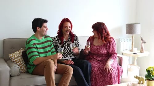 Non-binary person and curvy woman drinking wine on a sofa