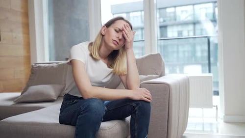 Woman Sitting on Sofa Looking Sad and Worried
