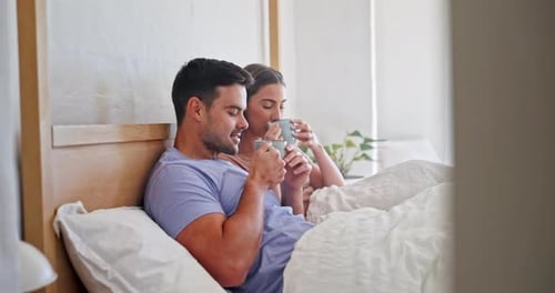 Happy Couple Relaxing Together Drinking Coffee in Bed