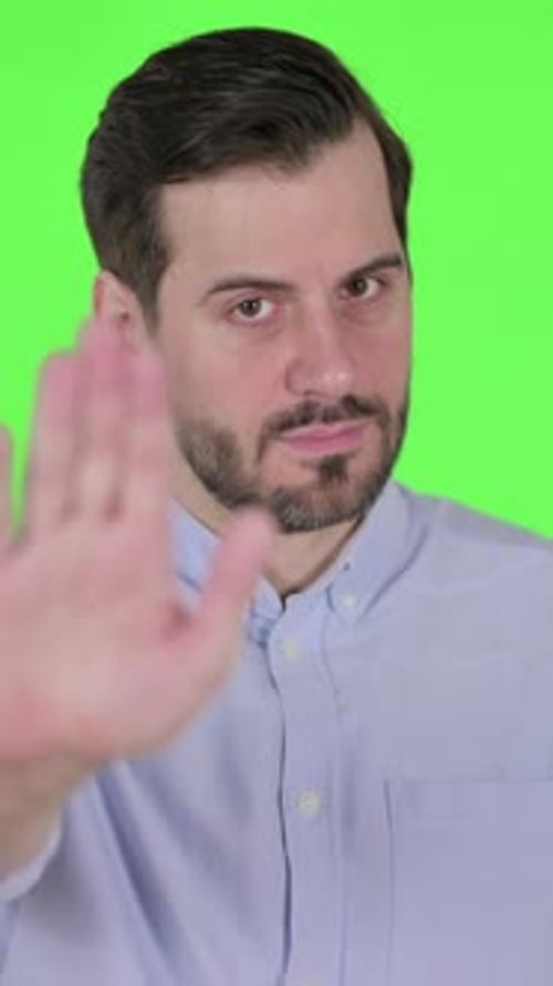 Porträt eines Mannes, der das Stoppschild von Hand zeigt, grüner Bildschirm, vertikales Video