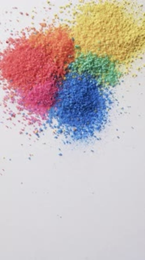 Vertical video of close up of multi coloured sand grains and copy space on white background