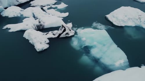 Wunderschöne schwarz-weiße Eisberge, die in einer Lagune in Island schwimmen, verschwinden im blauen Wasser