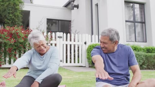 Happy senior diverse couple practicing yoga in garden