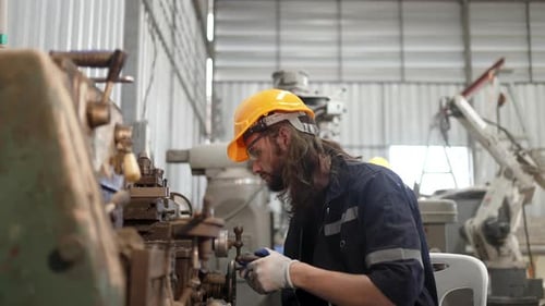 Blue collar workers at machine shop with welding robot arm.