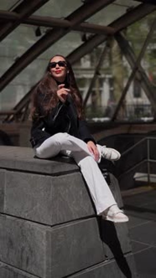 Stylish Woman Sitting on Ledge in Urban Setting