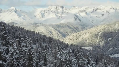 Montanhas cobertas de neve e encostas arborizadas iluminadas pela luz solar no Tirol do Sul, Alpes italianos