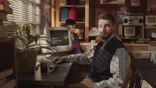 Portrait of Caucasian Geek Sitting at Desk by Old Computer
