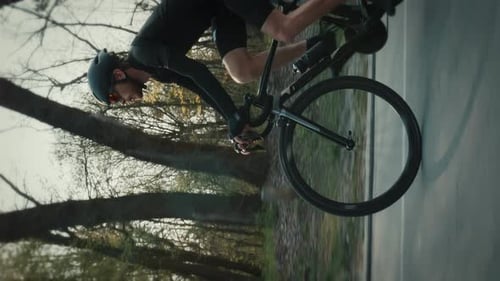 Sportive man in cycling apparel riding road bicycle in park. Vertical video