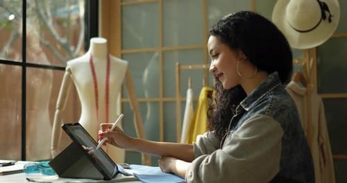 Woman Designs Fashion with Tablet in Sunny Studio