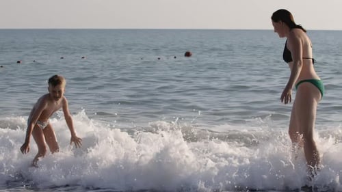 Woman and Boy Playing in the Ocean Waves