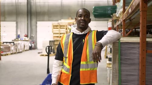Confident african american warehouse worker leans holding tablet smiling