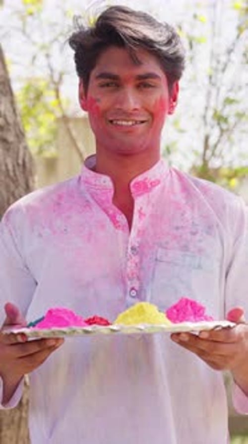 Smiling Man Holding Holi Powder on Tray Outdoors