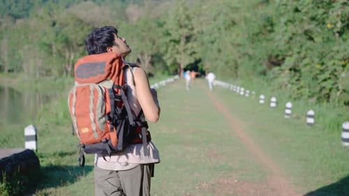 Young travel asian man walking on trail up peaceful lush high elevation green forest
