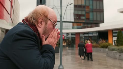 Man Coughing Outside on a Rainy Day