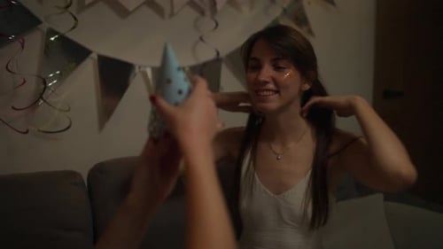A Happy Brunette Girl in a White Dress Chooses the Color of the Festive Cap That Will Suit Her