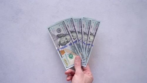 Man zeigt und legt fünf Einhundert-Dollar-Scheine in den Tisch. - Overhead