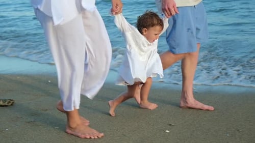Walking Family on Vacation By the Sea Dad and Mom are Holding the Hands of the Baby Family on