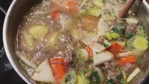 Stew with lots of vegetables carrots potatoes and meat cooked in a pot on an electric stove and is s