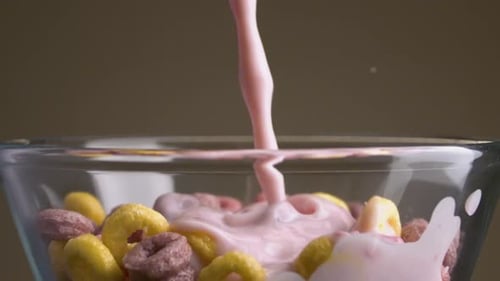 Pink Milk Pouring Into a Bowl of Colorful Cereal Rings