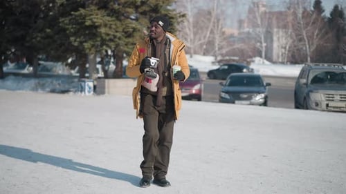 Camera Operator Walking Snowy Street Sipping Drink Under Soft Winter Light