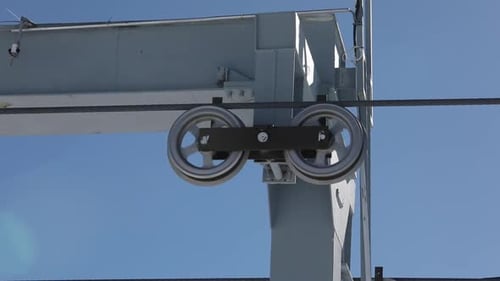 Cable Car Passing Over Wheels Atop of a Tower, Blue Sky Background, Close Up.