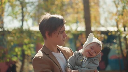 Affectionate Father Holding Small Baby in Sunny Park Environment Tender Moment Between Father and