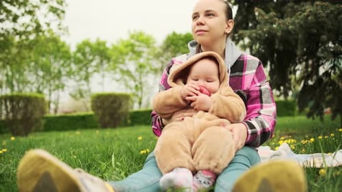 A Mother and Her Baby Enjoy a Beautiful Spring Day in the Park They are Sitting on a Blanket