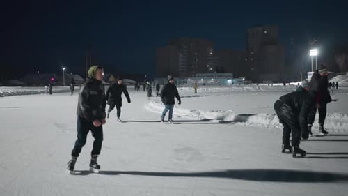 Young People Enjoying Evening Skating on Outdoor Ice Rink Under City Lights