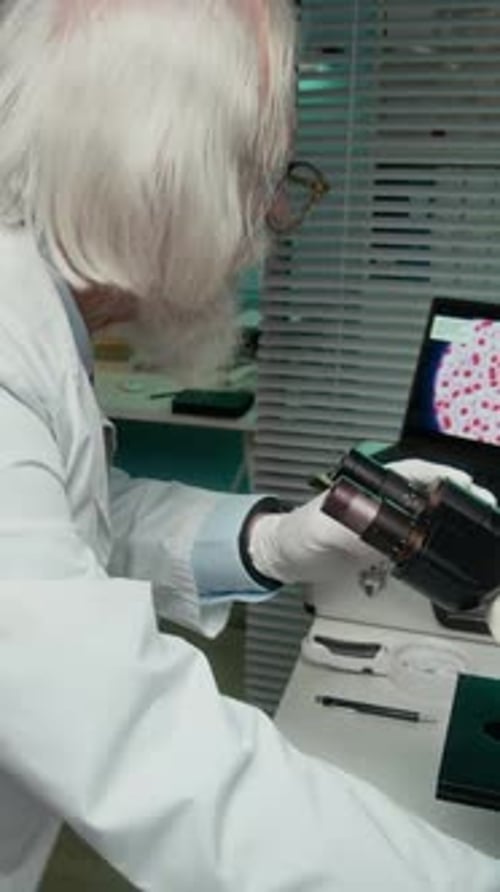 Researcher Examining Specimen Through Microscope in a Lab