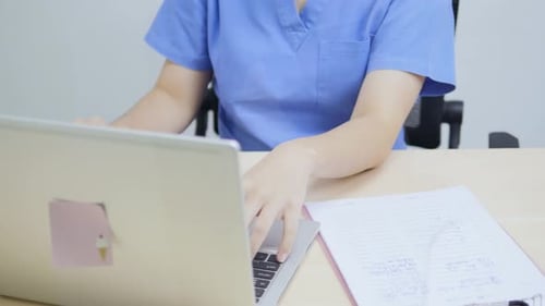 Health Worker Typing on Laptop in Bright Office