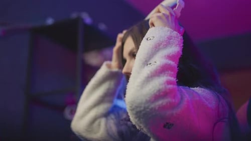 Rear View Gamer Placing Headphone and Resting Hand on Desk in Neon Setup