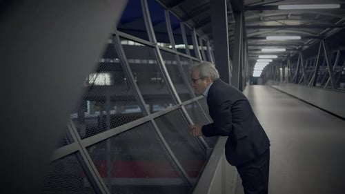 Mature Man in Suit Leans on Elevated Walkway at Night
