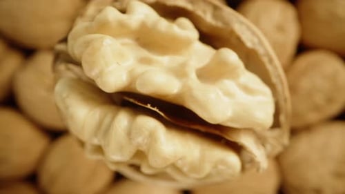 A top-down view of a partially peeled walnut slowly rotating and falling down among a pile