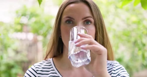 Thirsty Woman Drinking Water From Glass in the Garden Outdoors in Sunny Day