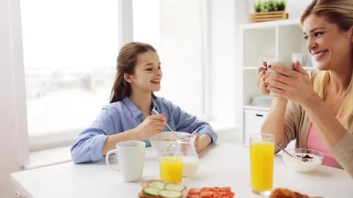 Blonde Woman and Girl Eating Breakfast at Table