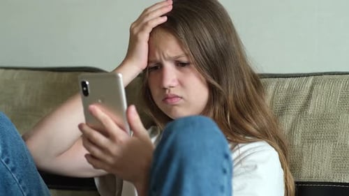 Worried Girl Looking at Phone Screen Indoors