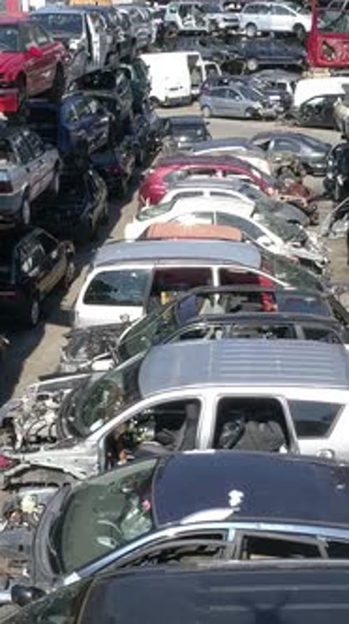 Vertikales Video einer Vielzahl beschädigter Autos, die auf einen Schrottplatz warten