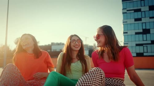 Young Female Skaters in Quad Rollers Resting on Rooftop